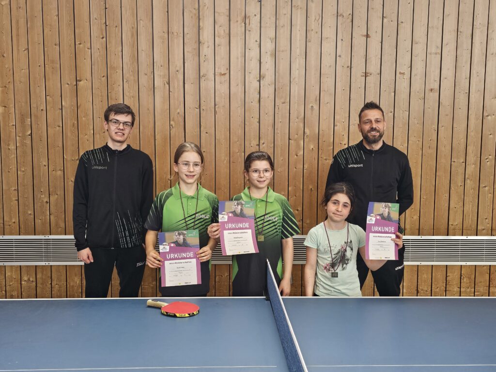 Die drei erfolgreichen Tischtennismädchen des DJK-SV Furth (v.l.n.r.): Sarah Venus, Sarah Jungwirth und Lora Daskalova mit ihren Betreuern Fabian Frankl (l.) und Shane Milligan (r.) bei der Bezirks-Minimeisterschaft 2025